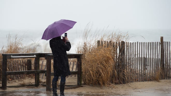 A beachgoer takes photos of the waves at Rehoboth Beach.